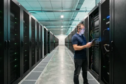 Technicien inspectant les serveurs dans une salle de data center moderne avec des rangées de racks illuminés